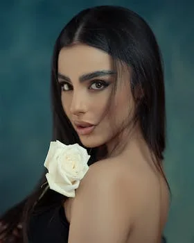 Studio portrait of a stunning brunette holding a white rose, showcasing beauty and elegance.