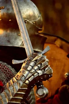 Detailed view of a medieval knight's steel gauntlet grasping a sword, highlighting historical armor.