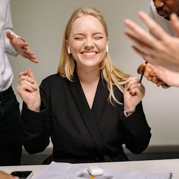 Happy woman smiling with closed eyes and earpods in a business meeting.